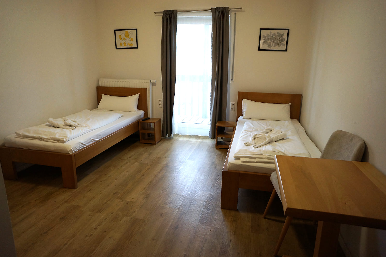 Standard Zweibettzimmer mit zwei getrennten Einzelbetten, Schreibtisch und Balkontür.
